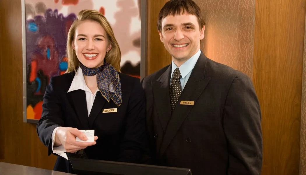 Concierge che accoglie ospiti hotel con sorriso servizio personalizzato e fidelizzazione clienti